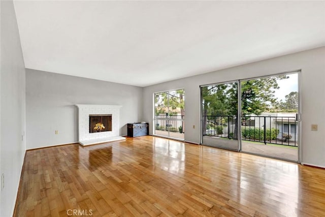 unfurnished living room with a brick fireplace and wood finished floors
