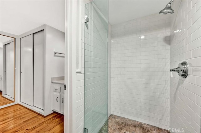full bathroom with tiled shower and wood finished floors