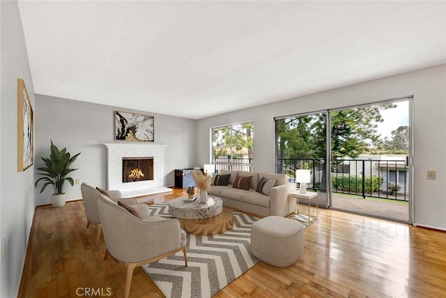 living room with a brick fireplace and wood finished floors