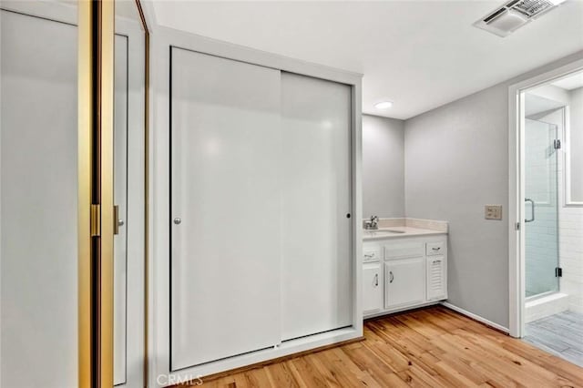 full bathroom with vanity, wood finished floors, visible vents, and a stall shower