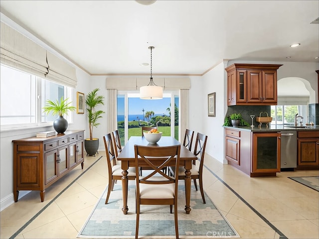 dining room featuring baseboards, light tile patterned flooring, recessed lighting, arched walkways, and crown molding