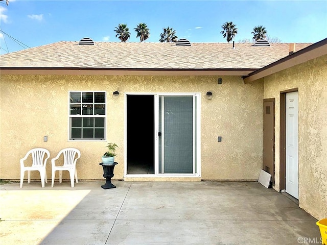 exterior space with a shingled roof, a patio, and stucco siding