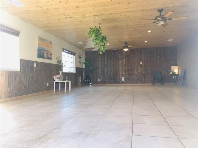 spare room featuring tile patterned floors, a wainscoted wall, wooden walls, and ceiling fan