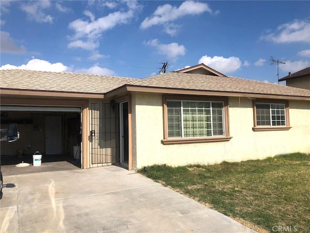 ranch-style home featuring roof with shingles, a front lawn, driveway, and stucco siding