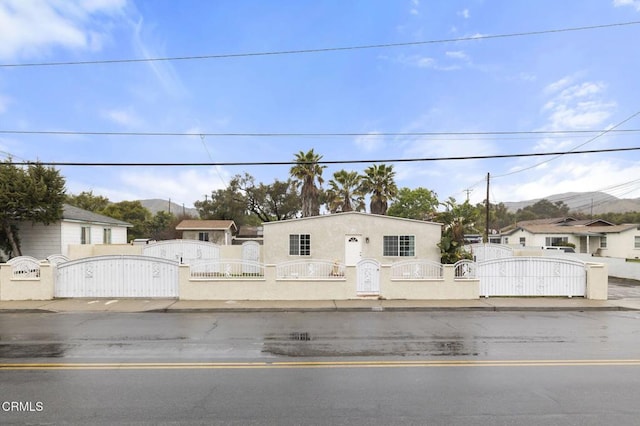 view of front of home with a fenced front yard, stucco siding, and a gate