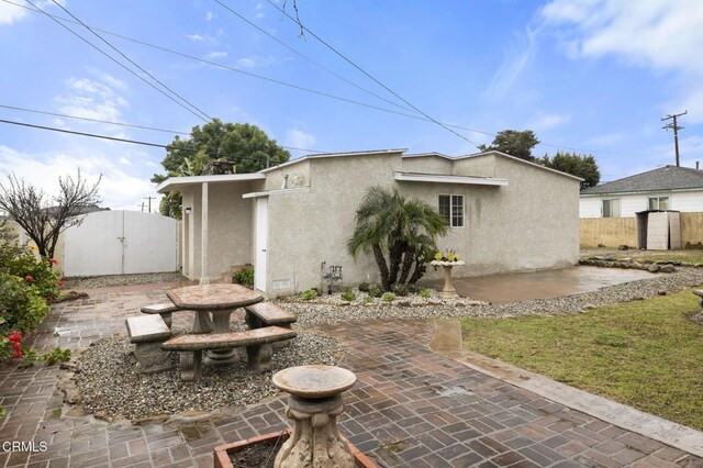 back of house with stucco siding, fence, and a patio area