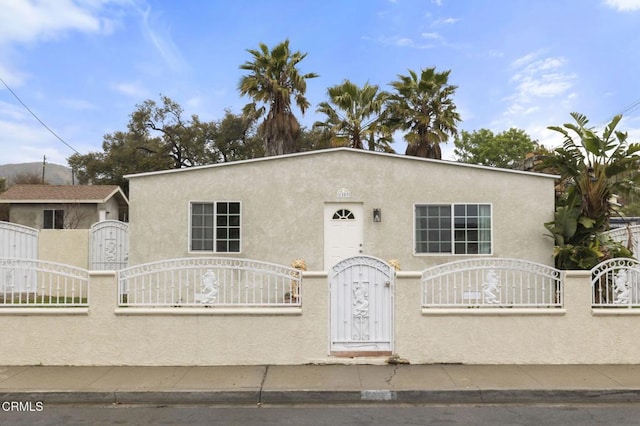 view of front of home with a gate, a fenced front yard, and stucco siding