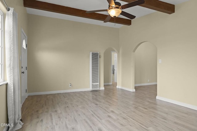 unfurnished room with a ceiling fan, baseboards, lofted ceiling with beams, light wood-style flooring, and arched walkways