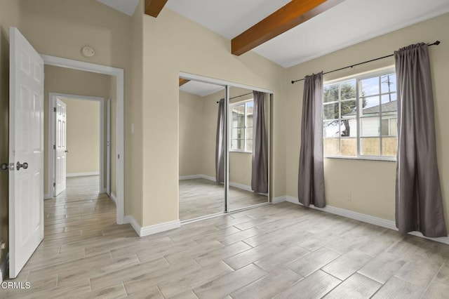 unfurnished bedroom featuring a closet, beamed ceiling, multiple windows, and wood tiled floor