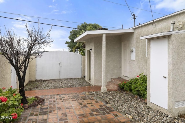 doorway to property with a gate, fence, and stucco siding