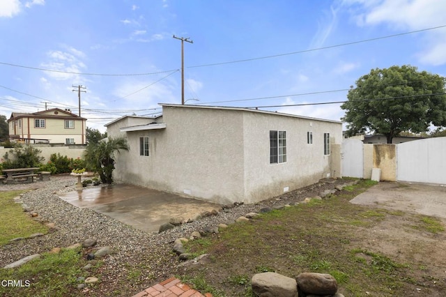 view of home's exterior with a gate, a patio area, fence, and stucco siding