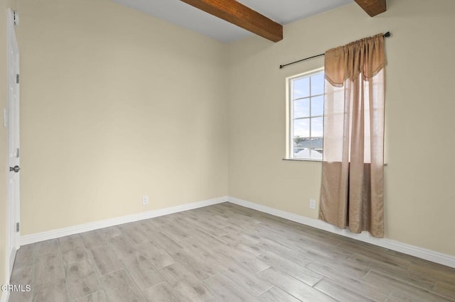 empty room featuring beam ceiling, baseboards, and wood finished floors