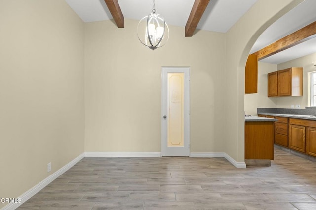 unfurnished dining area featuring baseboards, beam ceiling, light wood-style flooring, arched walkways, and a notable chandelier