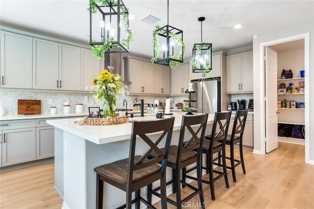 6288 Barb Way, Jurupa Valley, CA 92509 - kitchen with freestanding refrigerator, light countertops, gray cabinetry, light wood-type flooring, and decorative backsplash