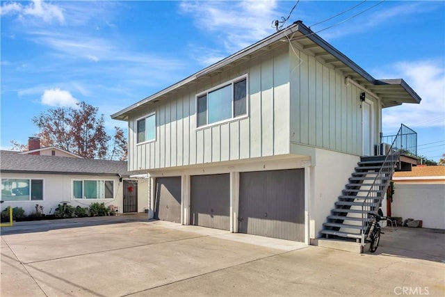 view of front facade with stairway, board and batten siding, driveway, and a garage