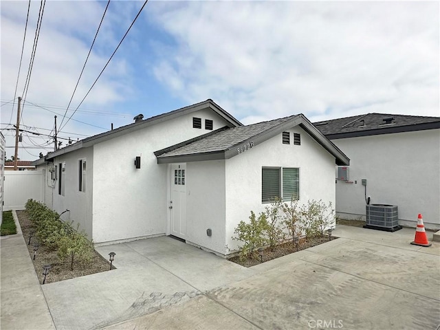 rear view of property with stucco siding, fence, cooling unit, and a patio area