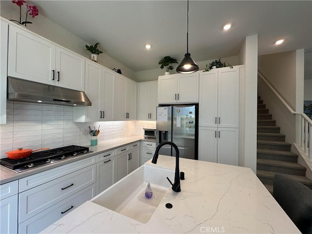 31937 Via Encima, San Juan Capistrano, CA 92675 - kitchen with appliances with stainless steel finishes, under cabinet range hood, tasteful backsplash, white cabinets, and decorative light fixtures