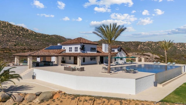 24949 Thunder Mountain Rd, Ramona, CA 92065 - back of property featuring an outdoor pool, an outdoor hangout area, roof mounted solar panels, and a patio
