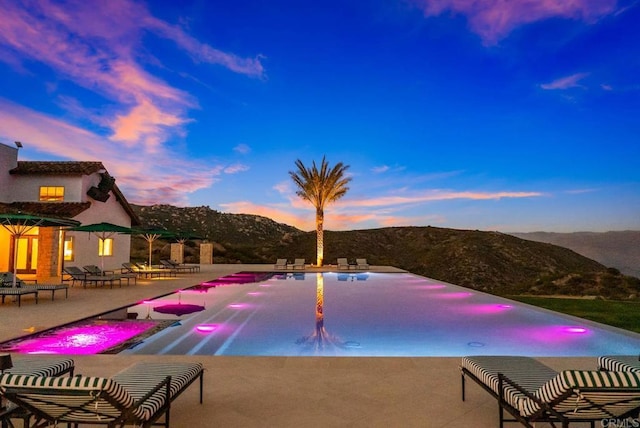 24949 Thunder Mountain Rd, Ramona, CA 92065 - pool at dusk featuring a mountain view, an infinity pool, and a patio area