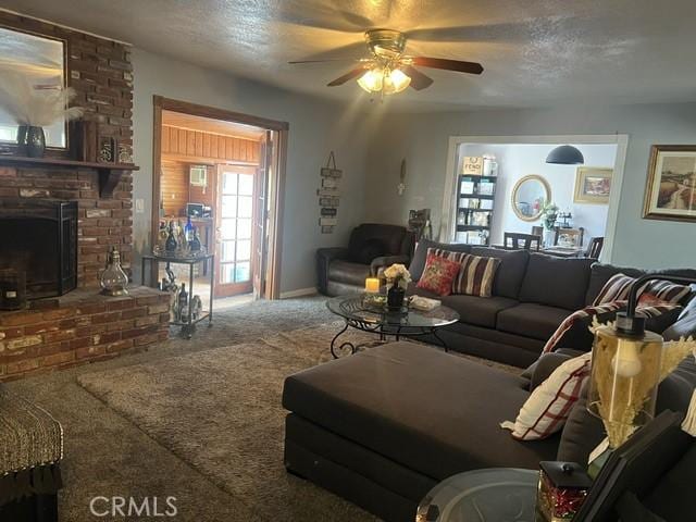 carpeted living room with ceiling fan, a textured ceiling, and a fireplace