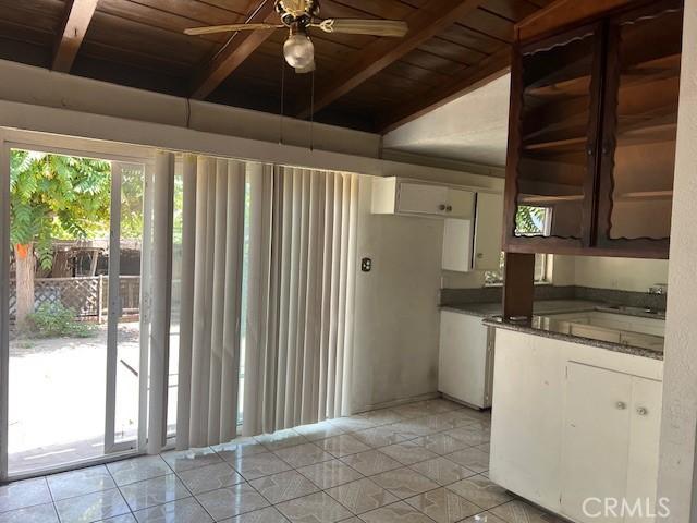 1320 N Grove Ave, Ontario, CA 91764 - kitchen featuring wooden ceiling with exposed beams, dark countertops, light tile patterned flooring, ceiling fan, and white cabinetry