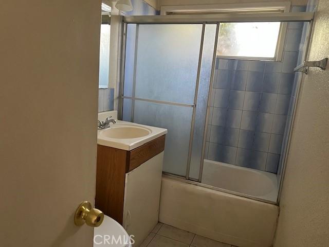 1320 N Grove Ave, Ontario, CA 91764 - full bath featuring toilet, vanity, tile patterned flooring, and bath / shower combo with glass door