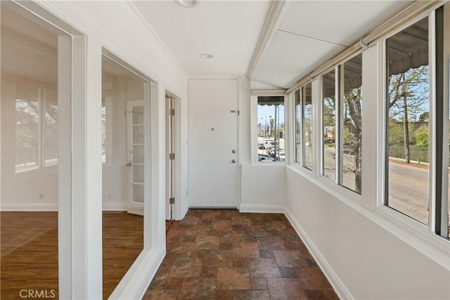 unfurnished sunroom with stone finish flooring and baseboards