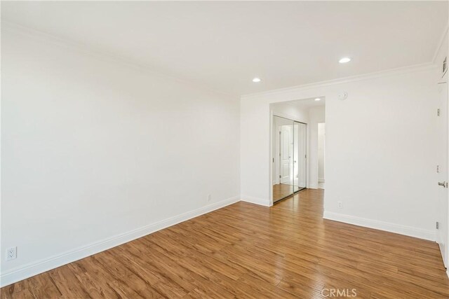 spare room with crown molding, light wood finished floors, recessed lighting, and baseboards