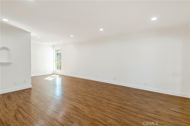 empty room featuring wood finished floors, crown molding, recessed lighting, and baseboards