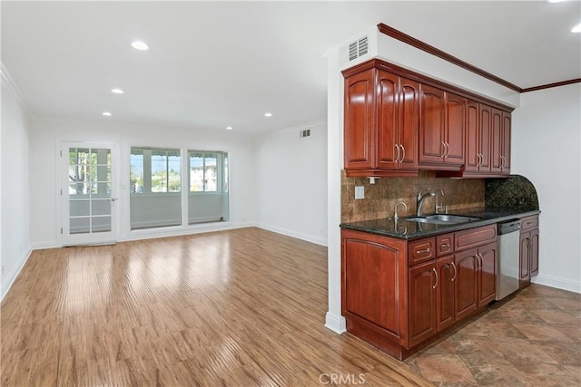 kitchen with ornamental molding, dishwasher, a sink, baseboards, and visible vents
