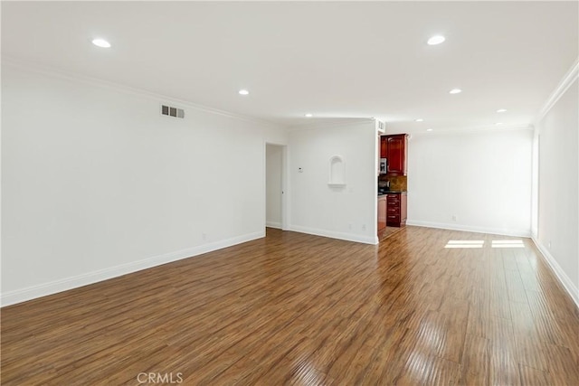 empty room featuring wood finished floors, visible vents, crown molding, and recessed lighting