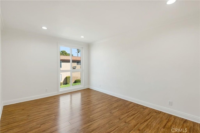 spare room featuring baseboards, recessed lighting, wood finished floors, and crown molding