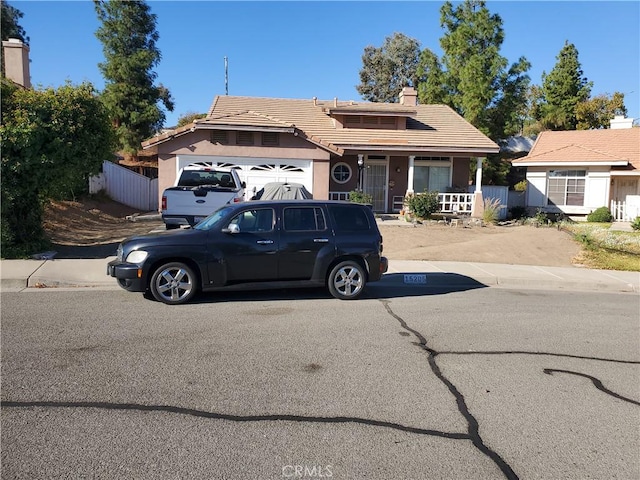 15205 Windjammer Way, Lake Elsinore, CA 92530 - view of front of house with a porch, an attached garage, a tile roof, stucco siding, and a chimney