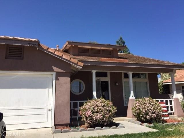 15205 Windjammer Way, Lake Elsinore, CA 92530 - view of front of house with a porch, stucco siding, and an attached garage
