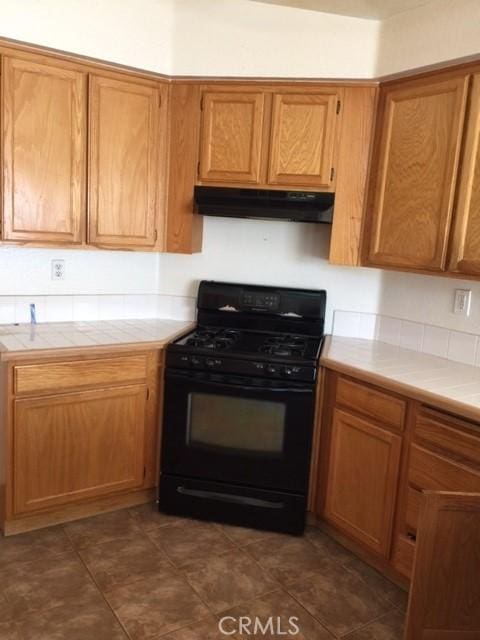 15205 Windjammer Way, Lake Elsinore, CA 92530 - kitchen featuring gas stove, tile counters, under cabinet range hood, and brown cabinetry