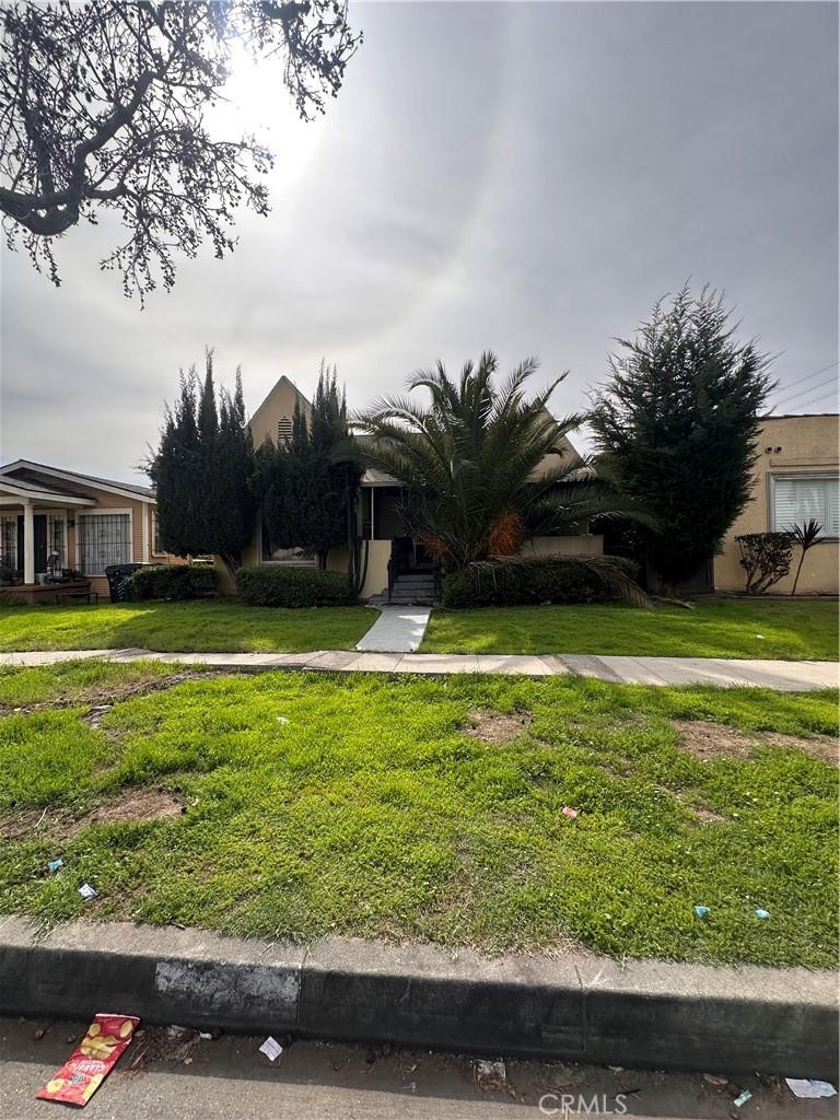 obstructed view of property with a front lawn and stucco siding