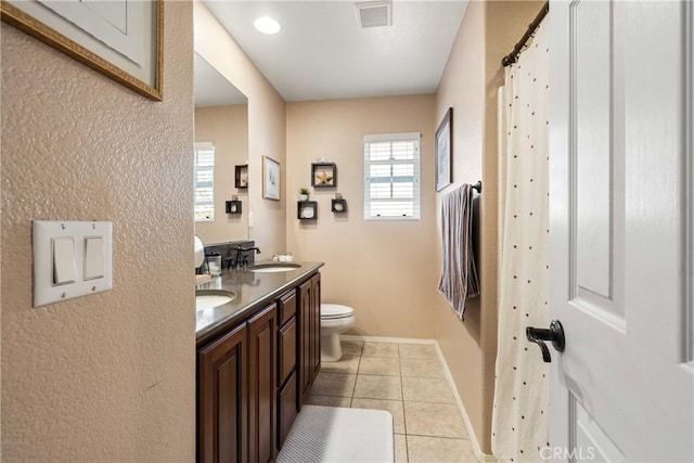 bathroom featuring a sink, double vanity, visible vents, toilet, and tile patterned floors