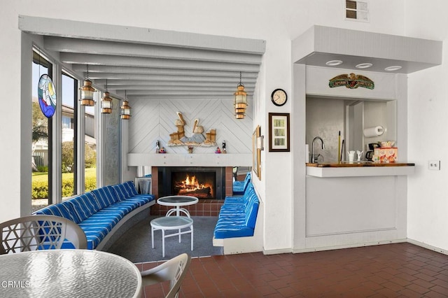living area featuring brick floor, a fireplace, visible vents, and baseboards