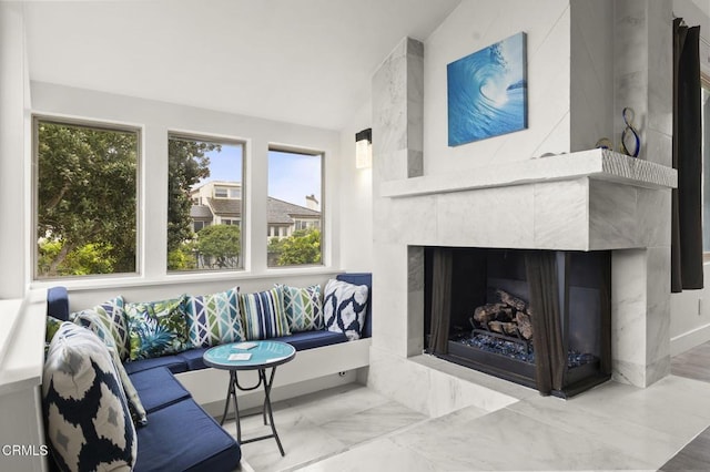 living area featuring a high end fireplace, vaulted ceiling, marble finish floor, and a wealth of natural light