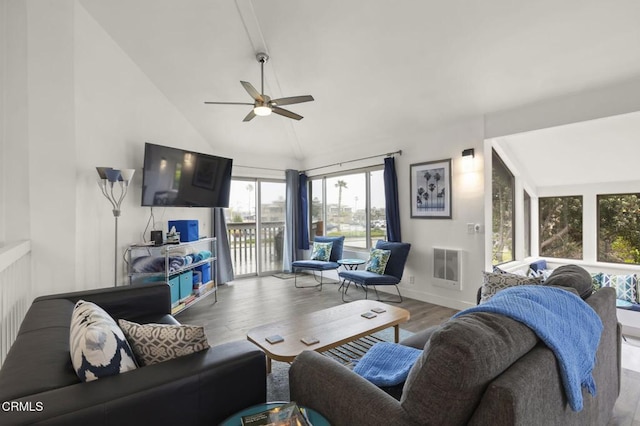 living room featuring heating unit, wood finished floors, a ceiling fan, baseboards, and vaulted ceiling