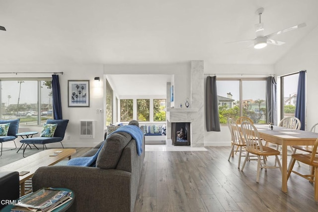 living room featuring hardwood / wood-style floors, a premium fireplace, a ceiling fan, and a healthy amount of sunlight