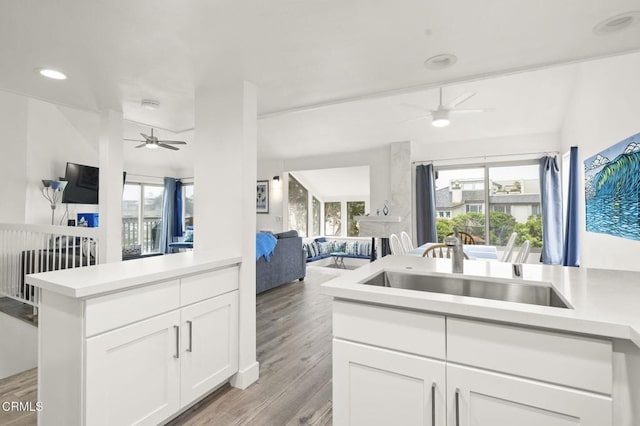 kitchen featuring a ceiling fan, light wood finished floors, a sink, light countertops, and open floor plan