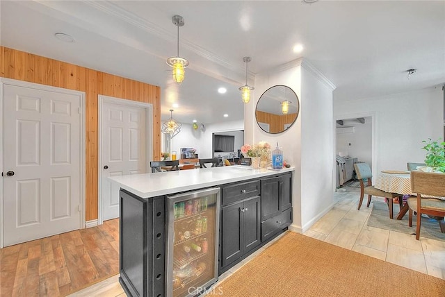1027 W Durness St, West Covina, CA 91790 - kitchen with wine cooler, light countertops, dark cabinets, crown molding, and decorative light fixtures