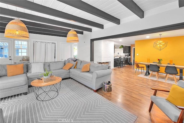 1027 W Durness St, West Covina, CA 91790 - living room with light wood finished floors, plenty of natural light, beam ceiling, and a chandelier