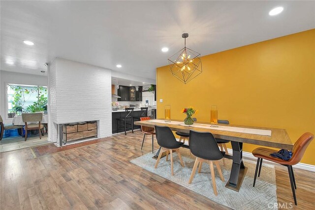 1027 W Durness St, West Covina, CA 91790 - dining room with light wood finished floors, recessed lighting, a brick fireplace, a chandelier, and baseboards
