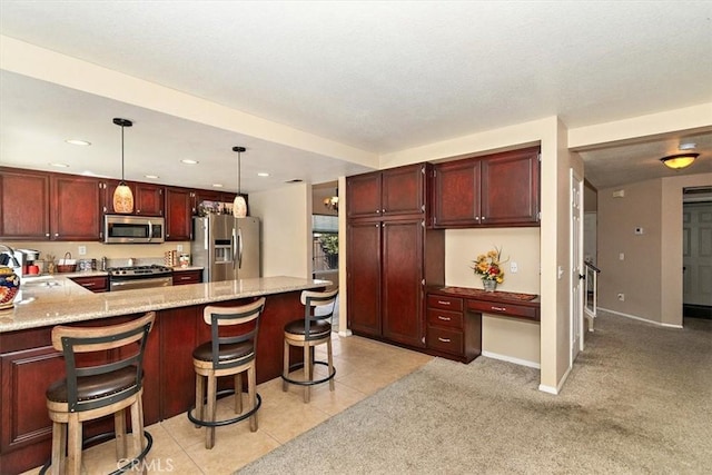 718 Cherry St, Corona, CA 92881 - kitchen featuring a sink, built in desk, appliances with stainless steel finishes, a kitchen bar, and decorative light fixtures