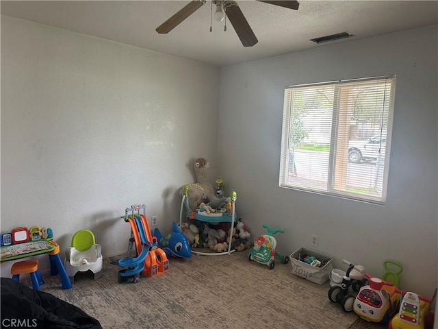 game room featuring a ceiling fan, visible vents, carpet floors, and a textured ceiling
