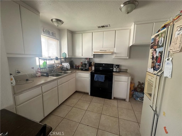 kitchen featuring visible vents, under cabinet range hood, freestanding refrigerator, black / electric stove, and a sink