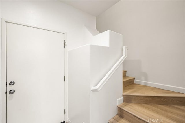 staircase featuring baseboards and wood finished floors