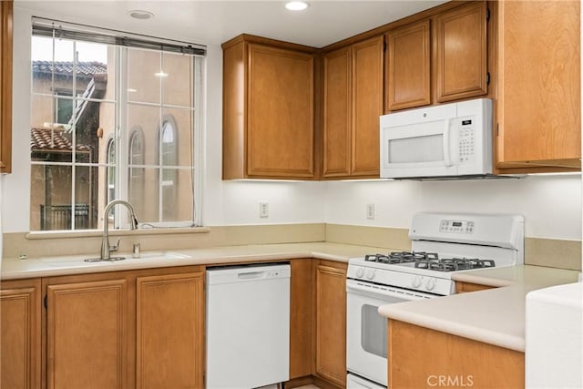 kitchen with a sink, light countertops, white appliances, brown cabinets, and recessed lighting